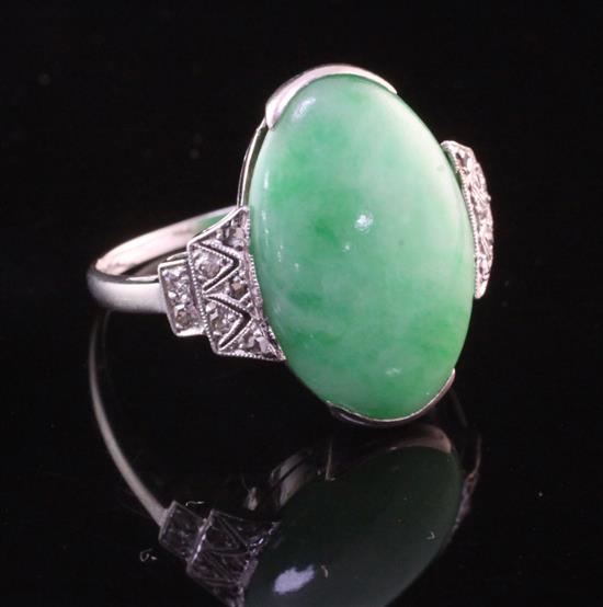 An 18ct white gold, cabochon jadeite oval ring with rose cut diamond set shoulders, size O.